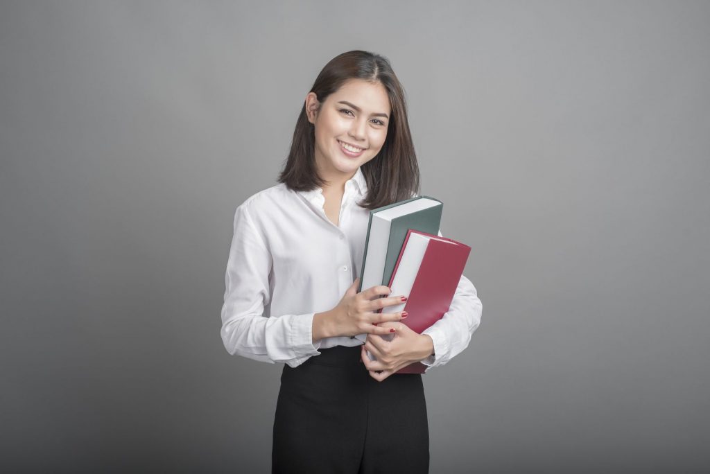 Beautiful teacher Woman holding book on grey background